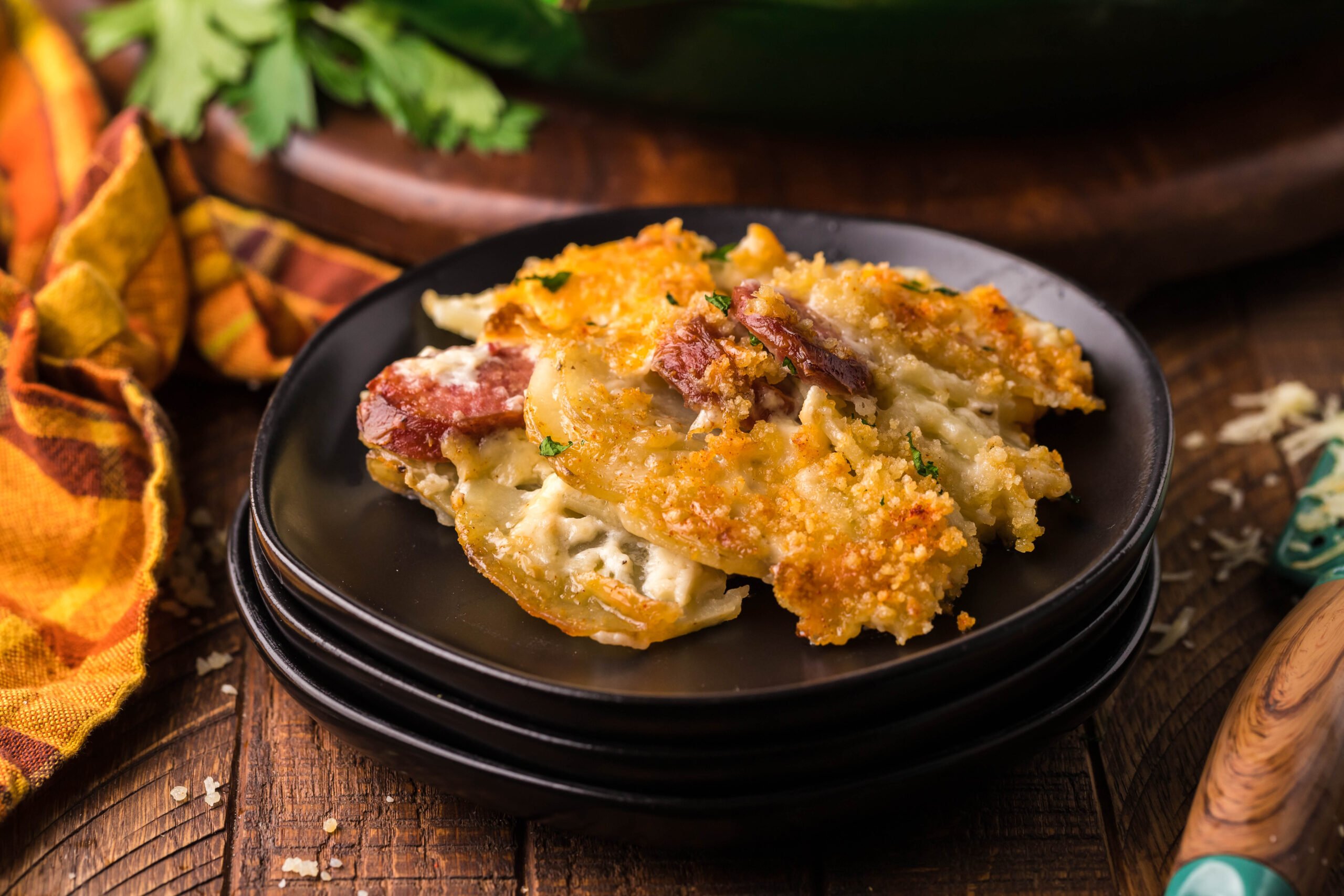 Front view of a serving of Au Gratin Potatoes & Ham on a black plate.