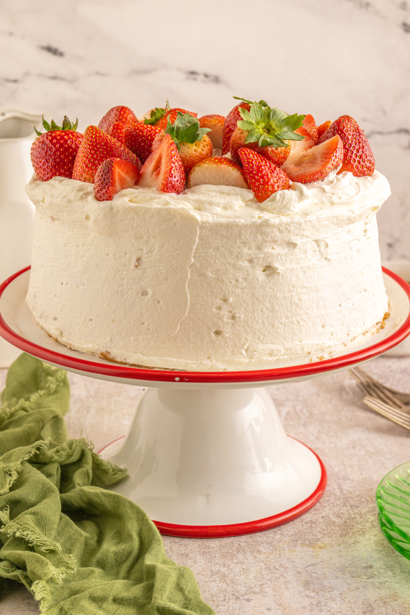 Strawberry Angel Food Cake topped with fresh strawberries and on a cake stand