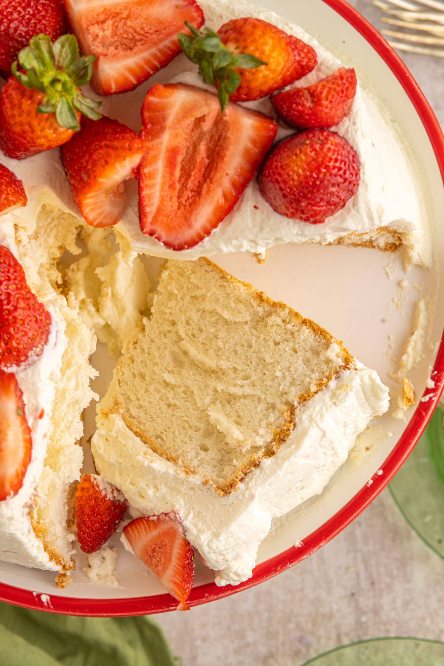 Overhead view of a cut piece of Strawberry Angel Food Cake on a white and red cake stand. 