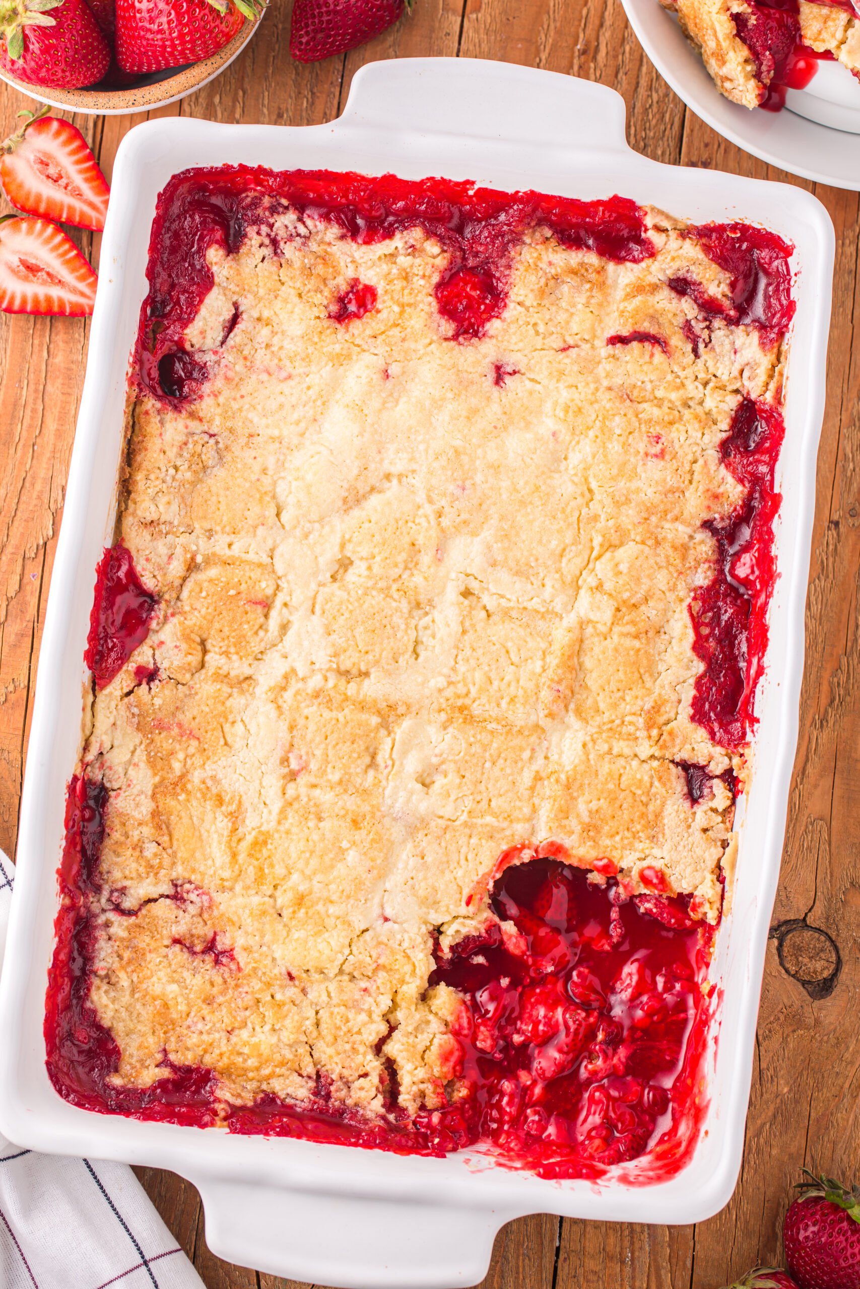 Overhead view of Strawberry Dump Cake in a white baking dish with a serving removed.
