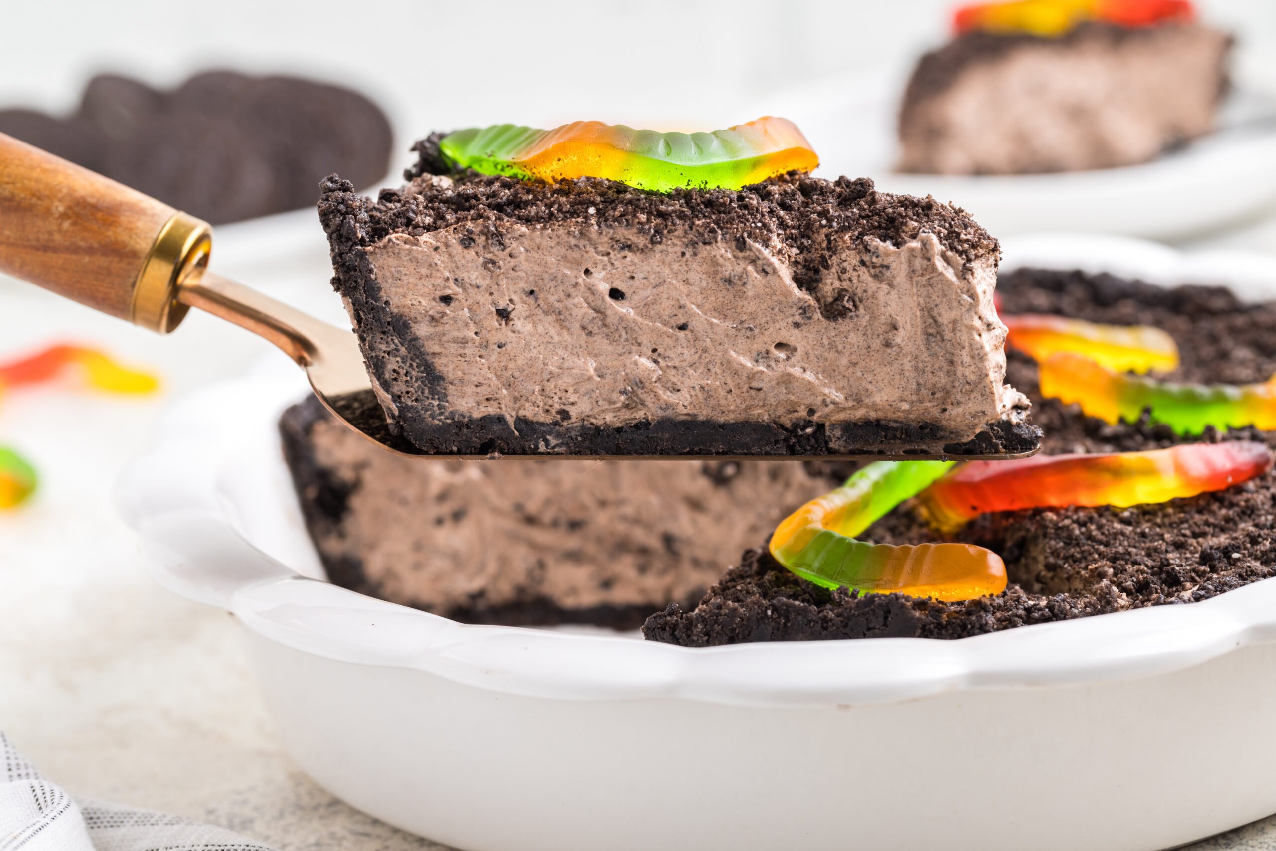 up close shot of oreo dirt pie slice being lifted up by a spatula