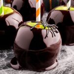 Black Candy Apples on table with fake spider sitting on top of it