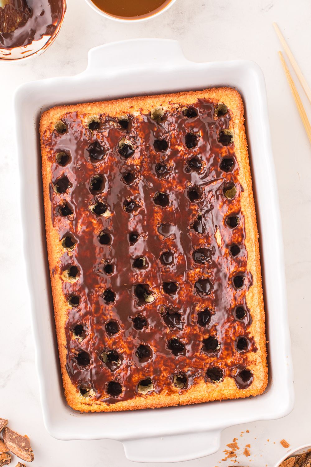 hot fudge spread allover the poke cake 