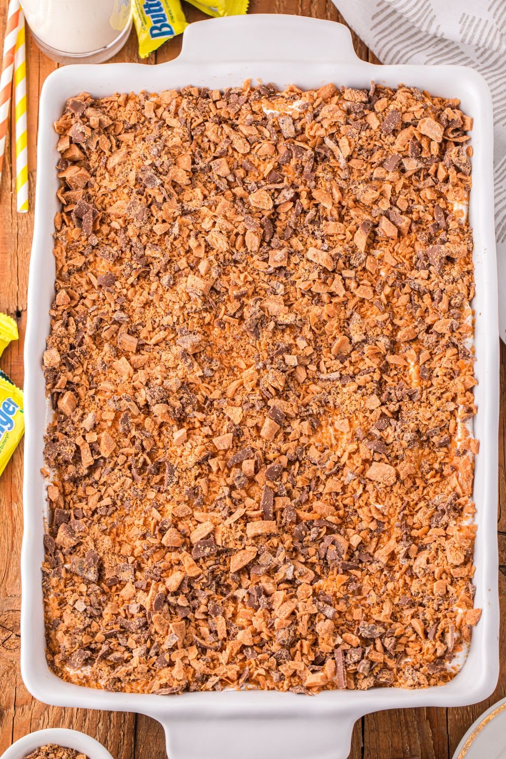 overhead look of poke cake in pan with butterfinger candy on top 