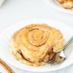Pumpkin Cinnamon Roll on plate with a fork on the side