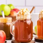 Crock Pot Caramel Apple Cider in a mason jar with whipped cream and syrup drizzled on top