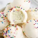 Lofthouse Sugar Cookie Truffles in a bowl with one that has a bite taken out of it