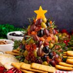 Antipasto Christmas Tree cheese ball on table with crackers around it