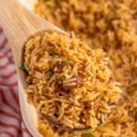 Stick of Butter Rice in pan with a wooden spoonful on table