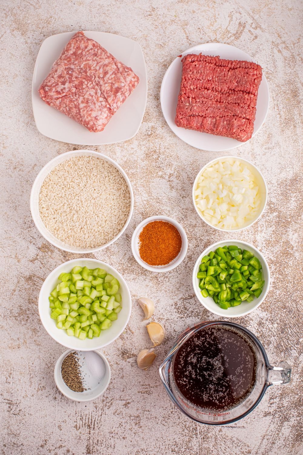ingredients for Dirty Rice sitting on a marble table in single serve bowls 