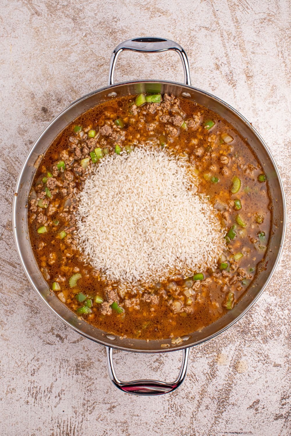 Dirty Rice - broth and rice added to meat mixture on table