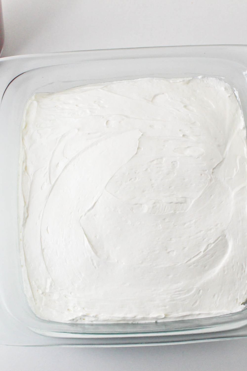 No Bake Strawberry Delight in pan with a whippd cream layer spread over the top