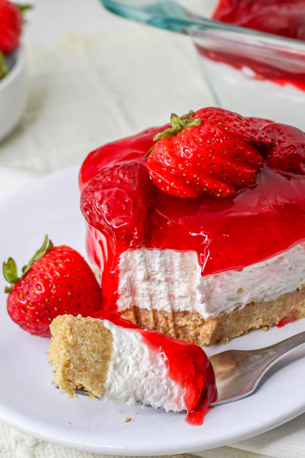 No Bake Strawberry Delight on plate with a fork with a bite on it and berry on plate 