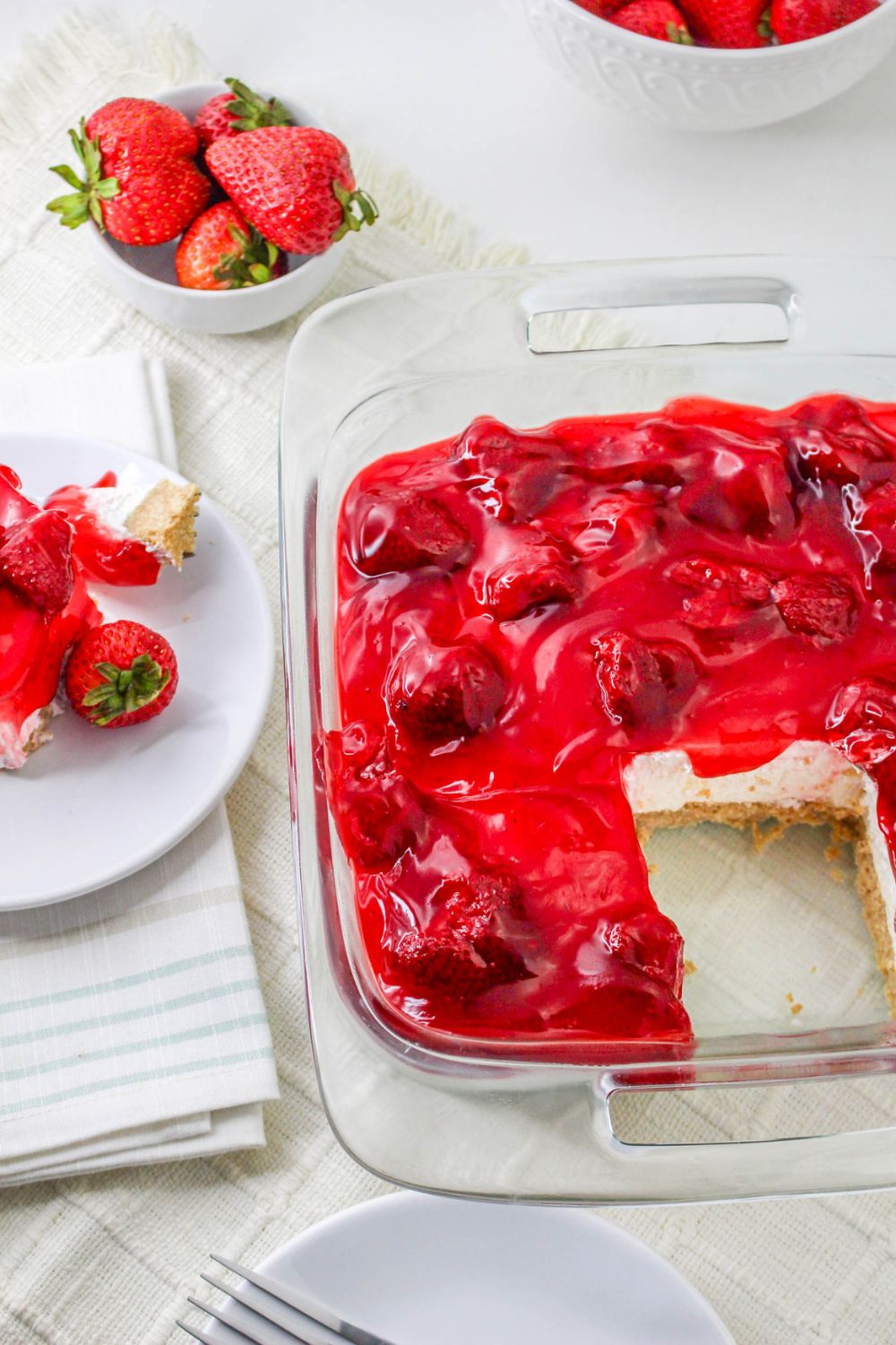No Bake Strawberry Delight in a glass pan with a slice taken out of it 