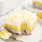 Lemon Blueberry Lush sliced on plate with a fork with a bite on it