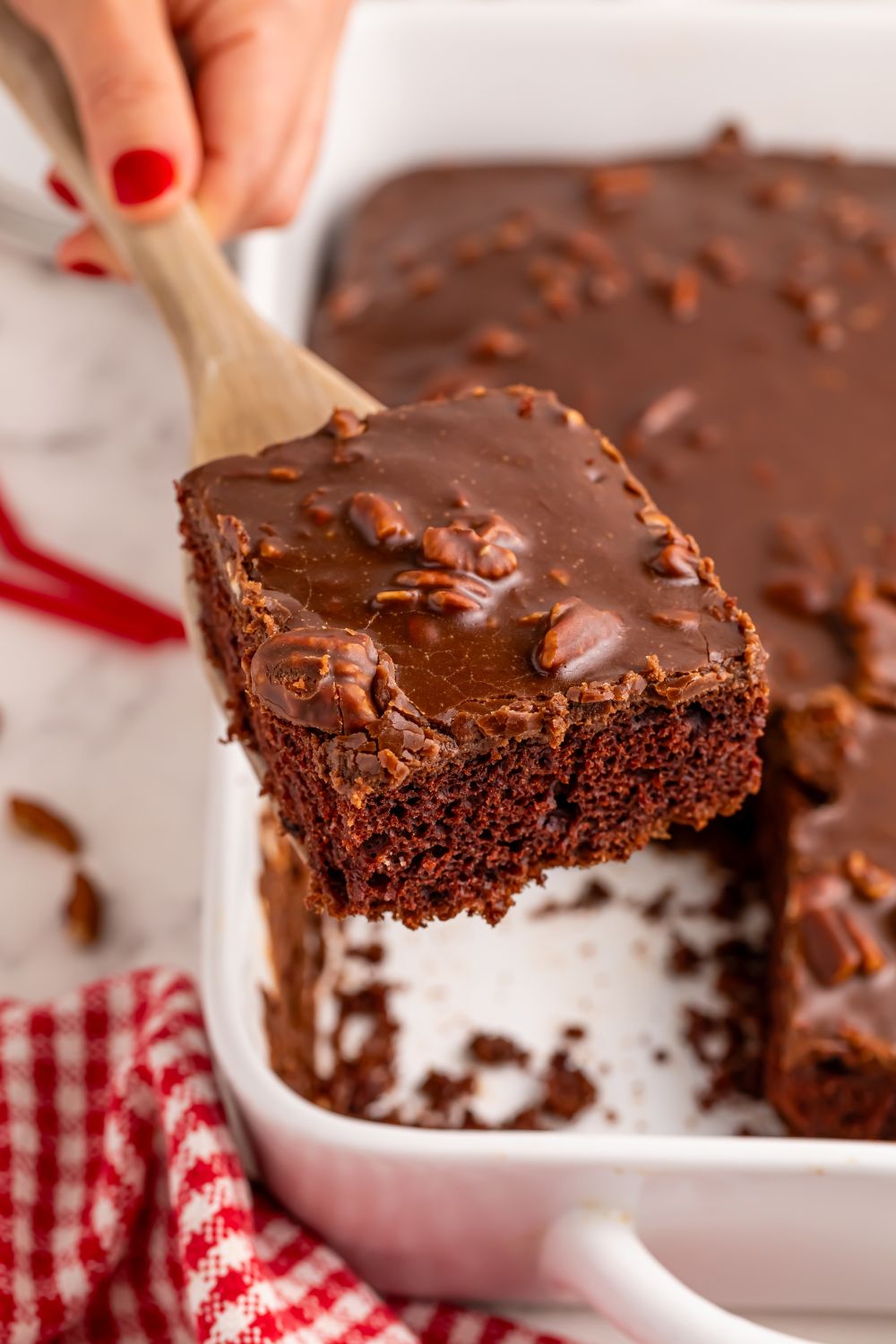 Dr. Pepper Cake in pan with a spatula holding one slice of cake