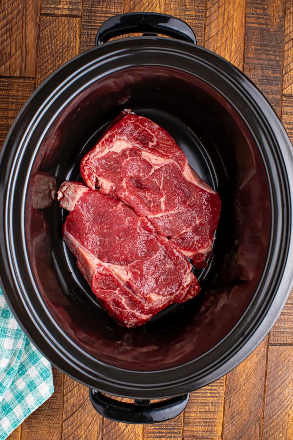 raw steak in the crockpot on table for the Crock Pot Steak and Potatoes recipe 