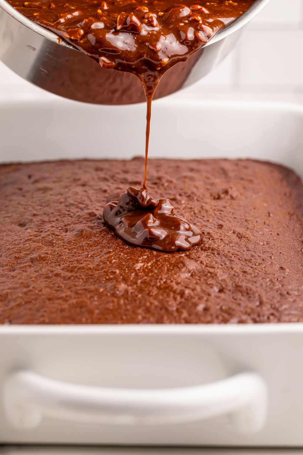 pouring a glaze over the top of a Dr. Pepper Cake