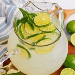 Limeade in a pitcher topped with sliced limes and mint leaves