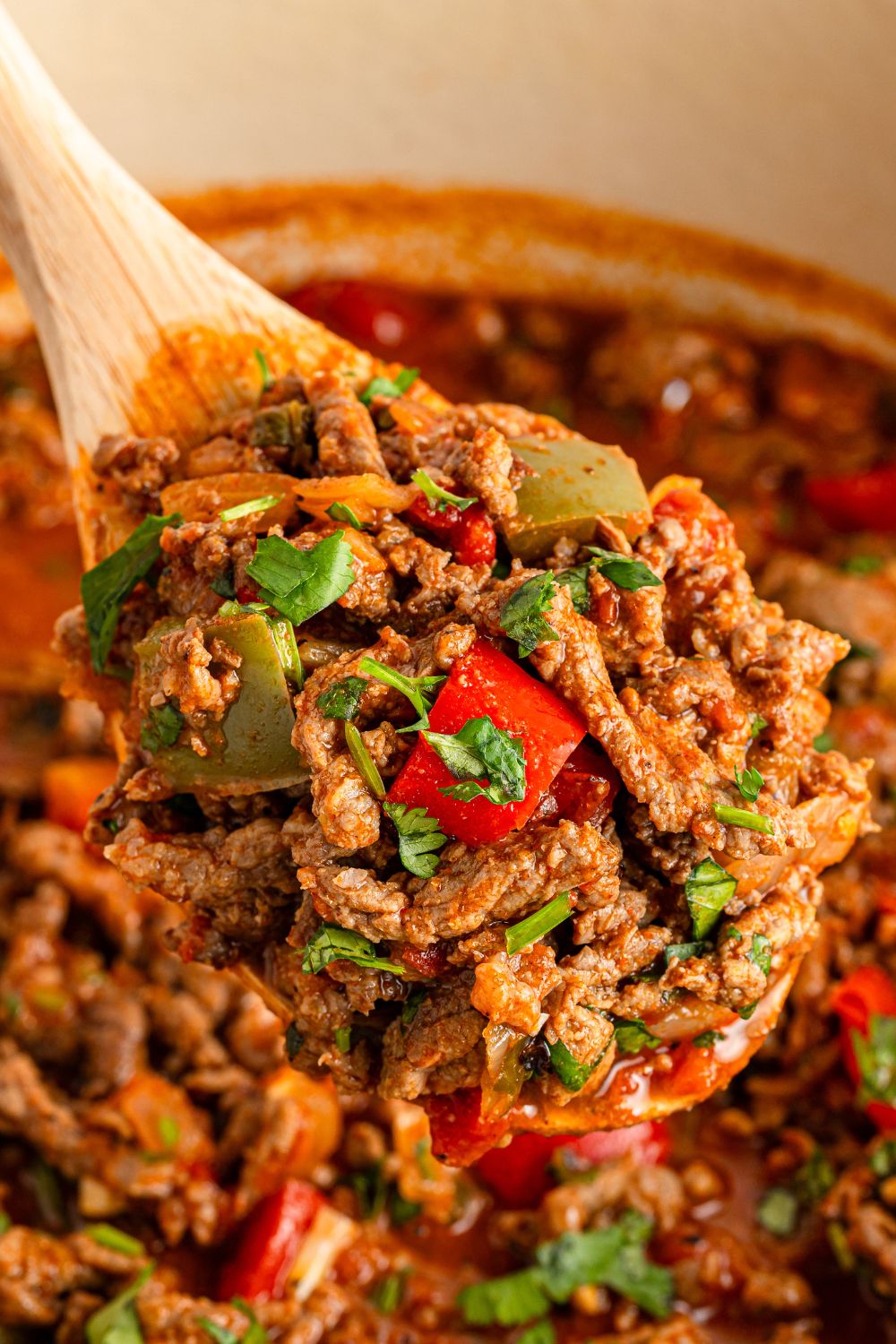wooden spoon over Dutch Oven with beef picada on the spoon 