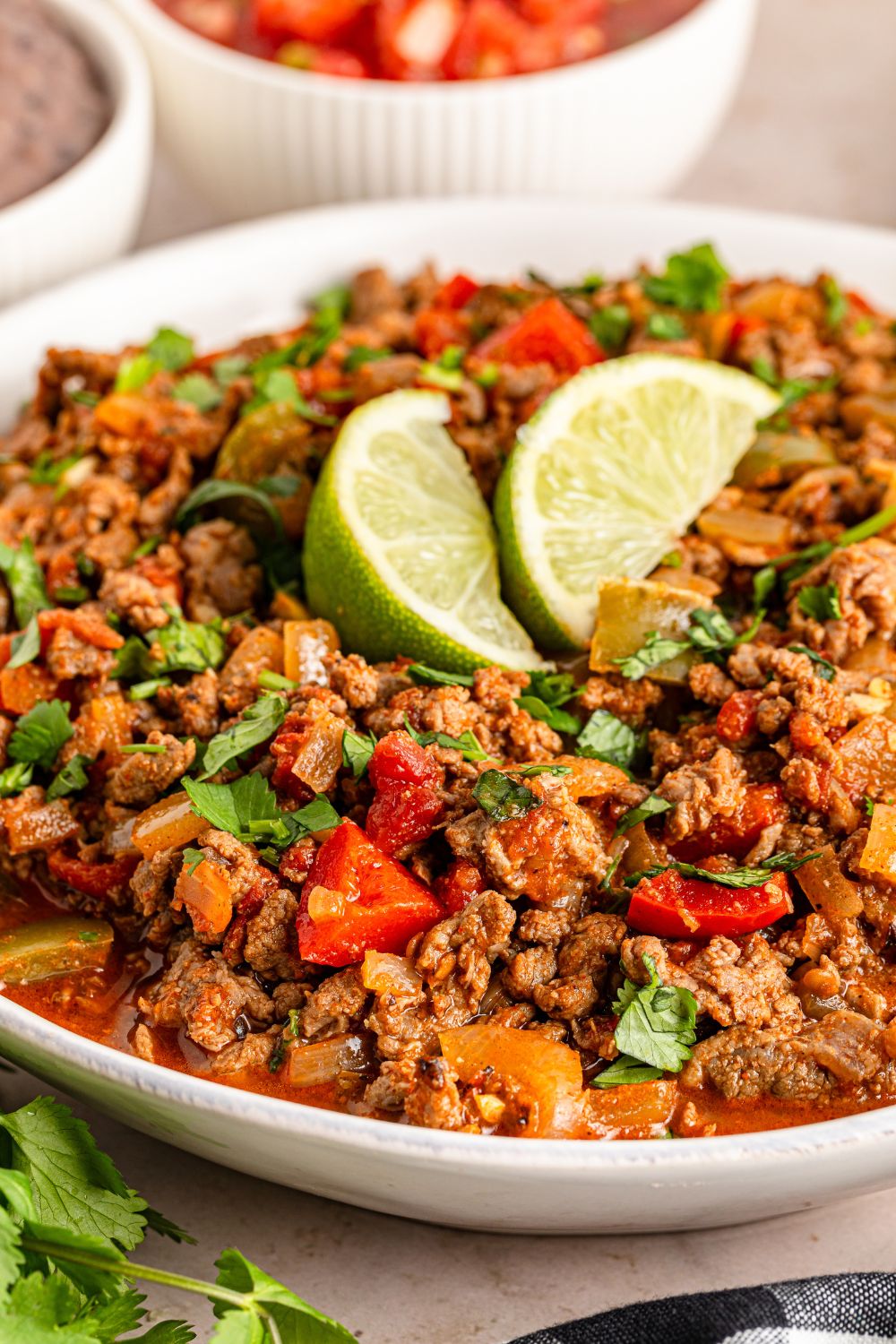 Carne Picada in a large bowl with cilantro and lime on top sitting on a table 
