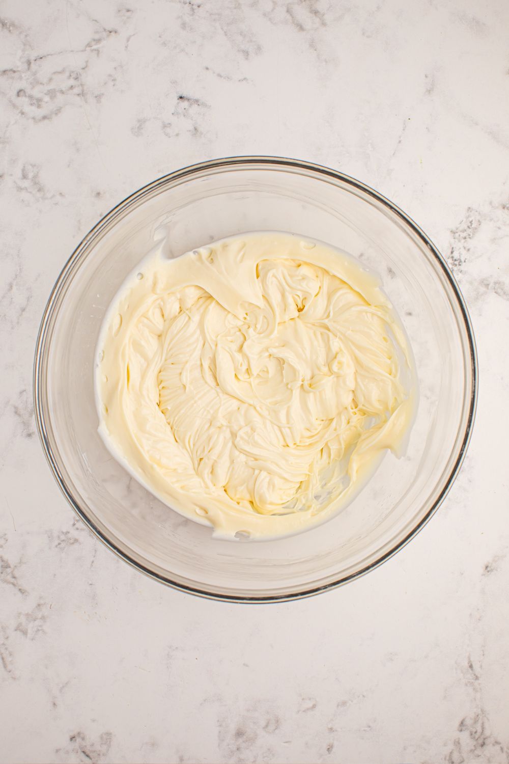 cheesecake mixture mixed up in a glass bowl on table 