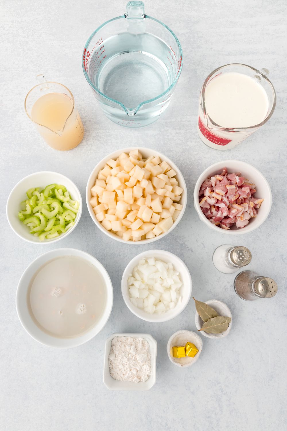 ingredients for clam chowder sitting in small bowls on table to show all the ingredients