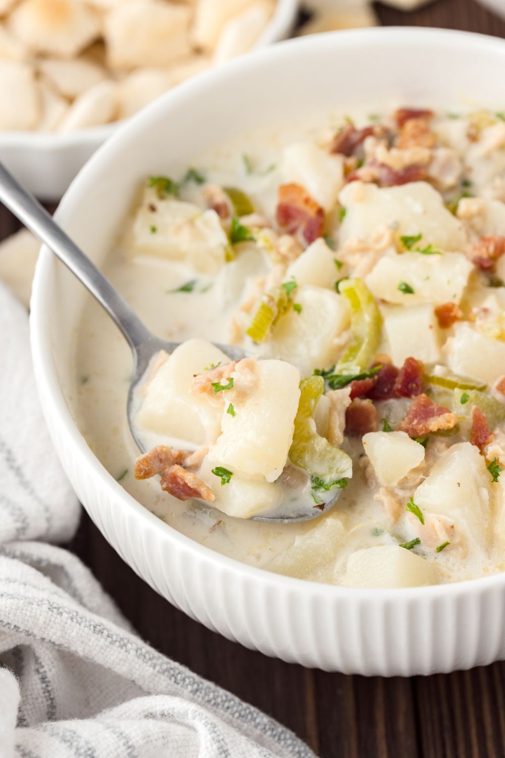 New England Clam Chowder in a white bowl with a spoonful of soup in bowl 