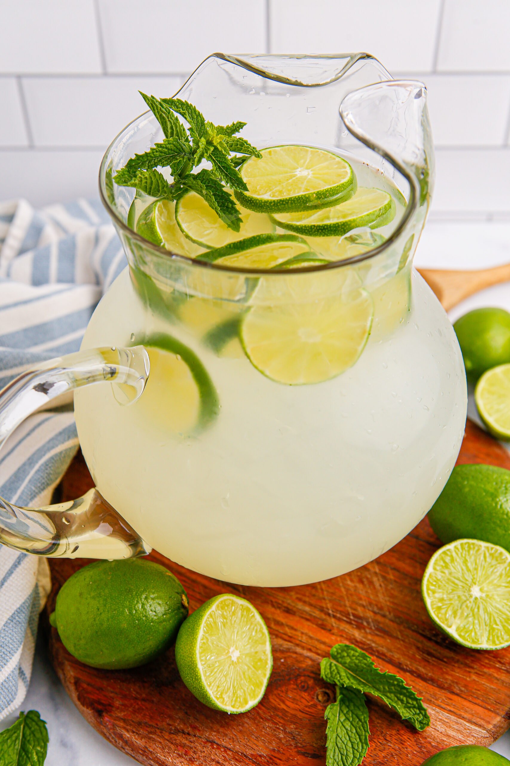 overhead look of pitcher with limeade in it, and scattered limes on table 