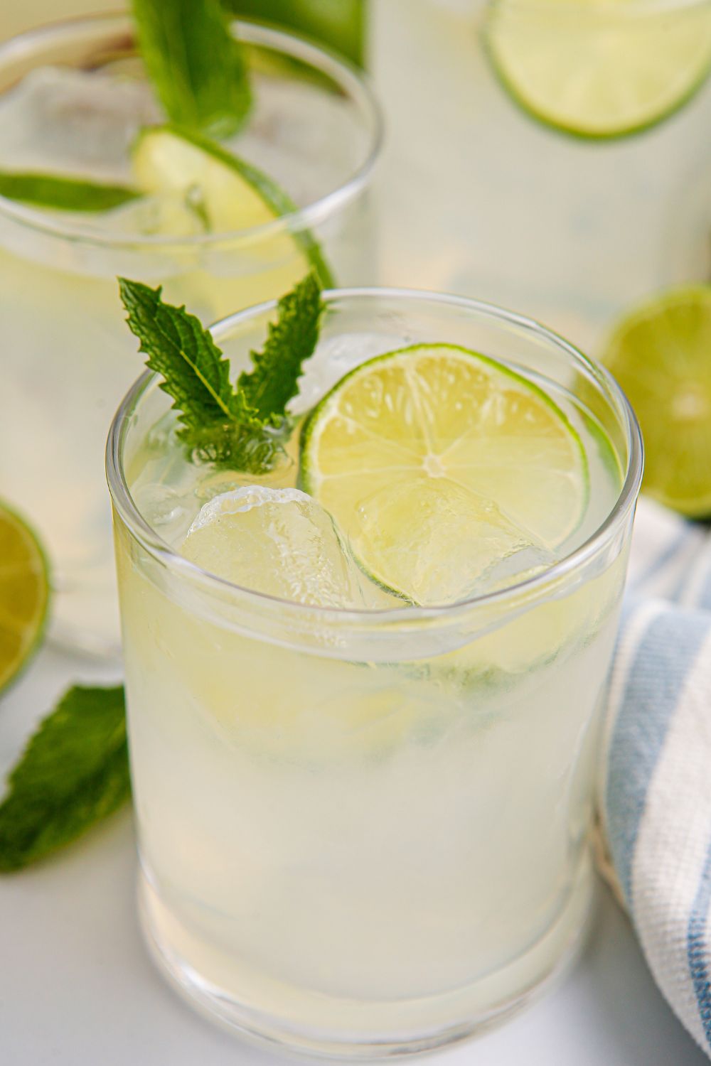 limeade drinks in glasses with sliced limes and mint leaves in each glass