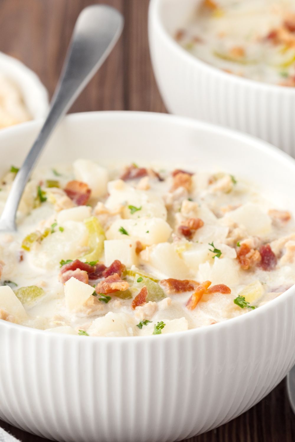 bowls of clam chowder on table with a spoon sitting in the bowl