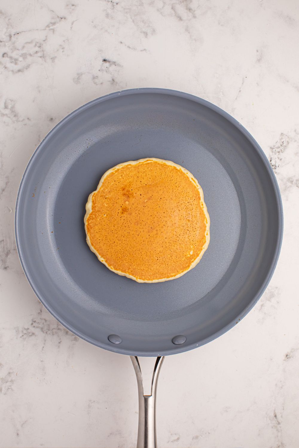 skillet with a pancake cooked in the center of pan 