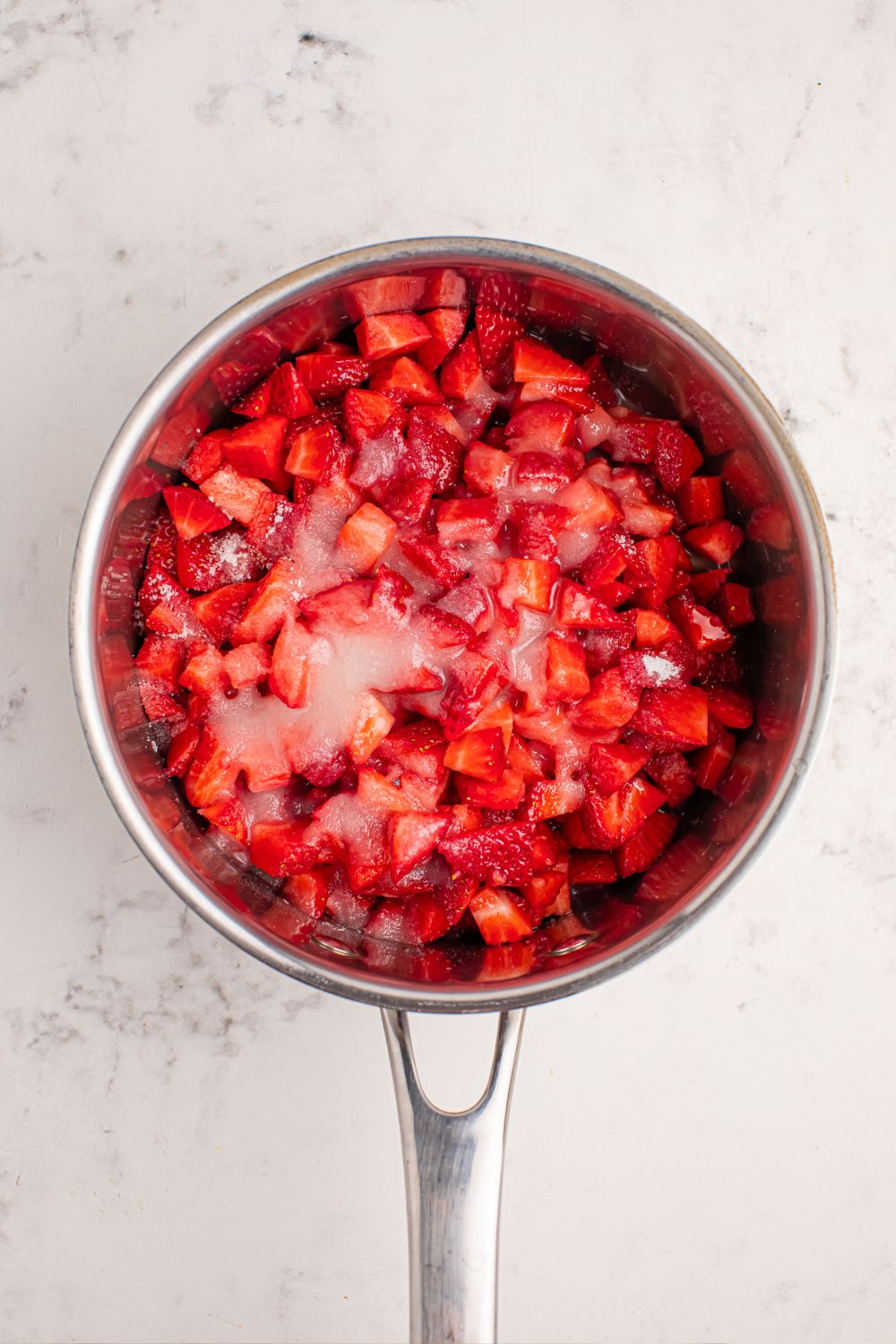 diced strawberries and sugar in a pan on counter 