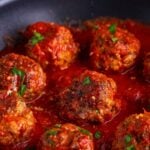Classic Italian Meatballs in a pan with some sauce over the top of the meatballs