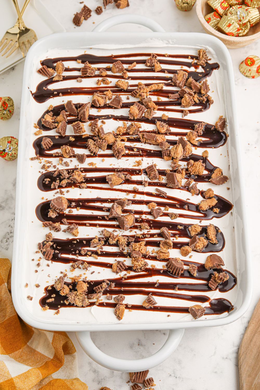 overhead Reeses Lasagna in a baking dish on table with candies scattered around
