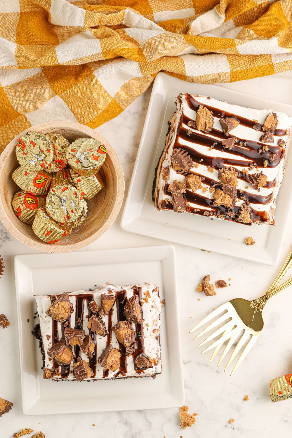 table with slices of Reeses Lasagna on them and bowl of candy and forks around plates 