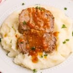 Crock Pot Apricot Pork Tenderloin sliced and sitting on top of mashed potatoes on a plate