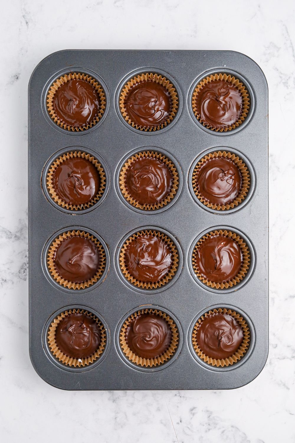 wet chocolate in muffin tin for making Peanut Butter Marshmallow Cups
