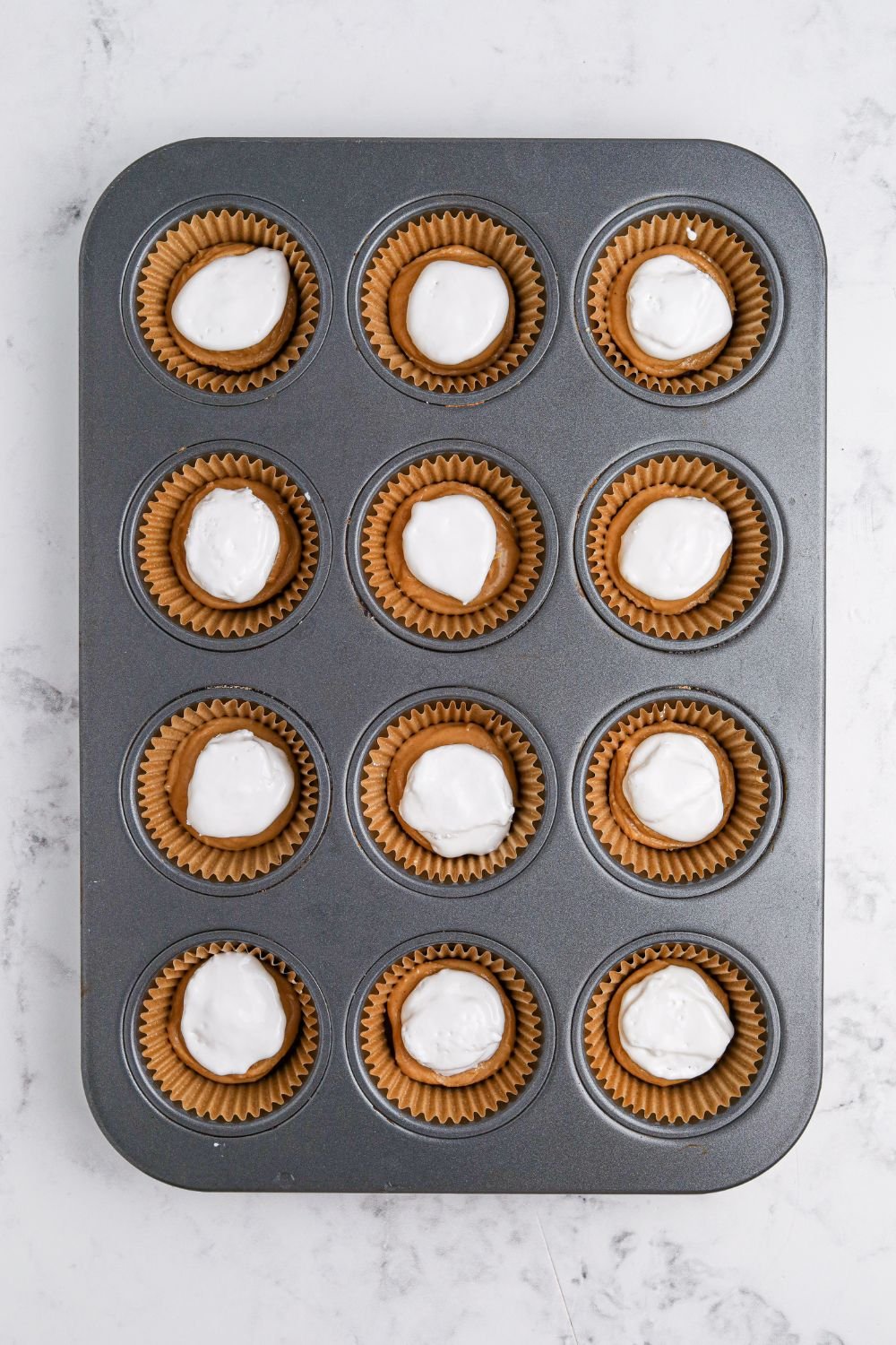 marshmallow cream on top of peanut butter in muffin cups 