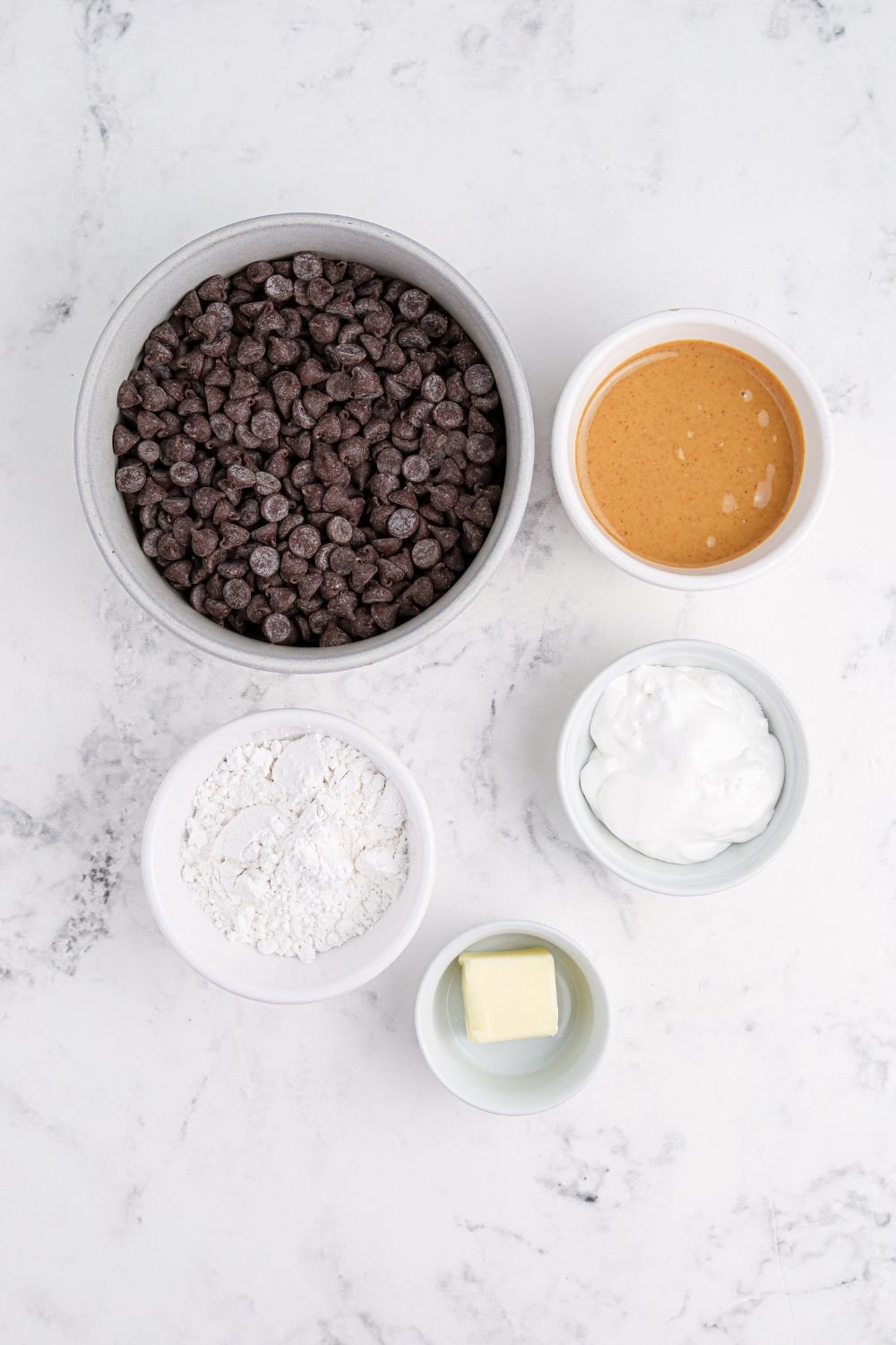 ingredients for Peanut Butter Marshmallow Cups in bowls sitting on marble counter 
