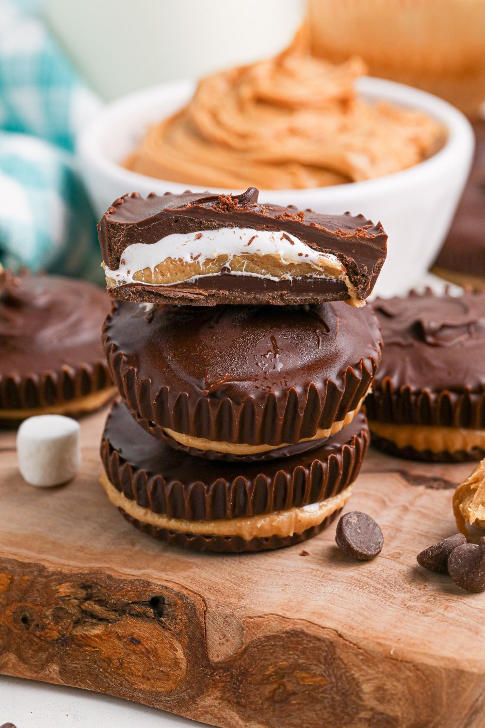 stack of Peanut Butter Marshmallow Cups on table with marshmallows and chocolate around it 
