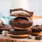 Peanut Butter Marshmallow Cups stacked on wooden cutting board with top one cut in half so you can see the layers