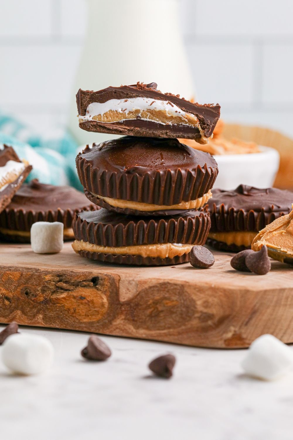 Peanut Butter Marshmallow Cups stacked on wooden tray with one cut in half to see layers 
