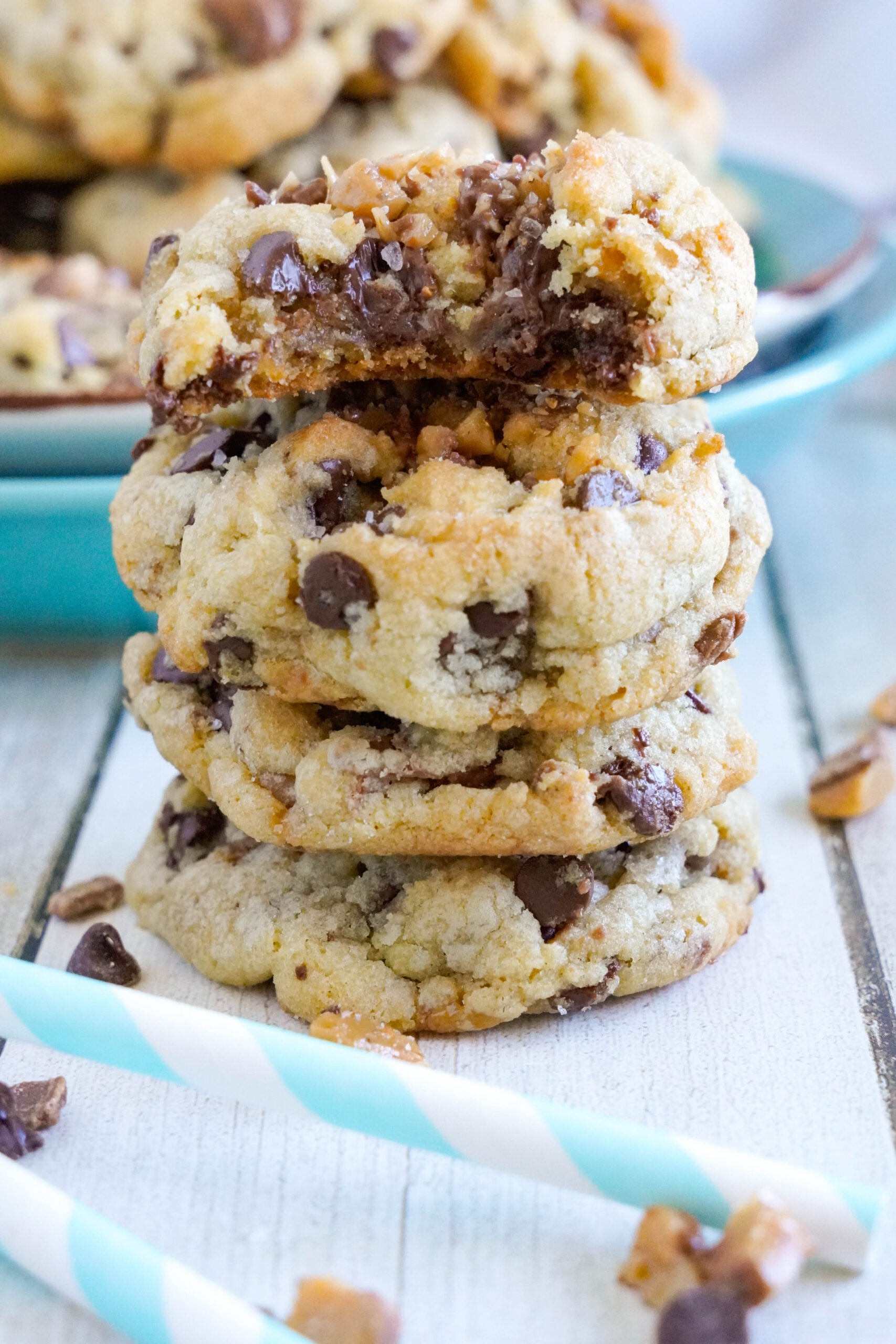 Chocolate Chip Toffee Cookies stacked on top of each other with crumble of cookies around it 