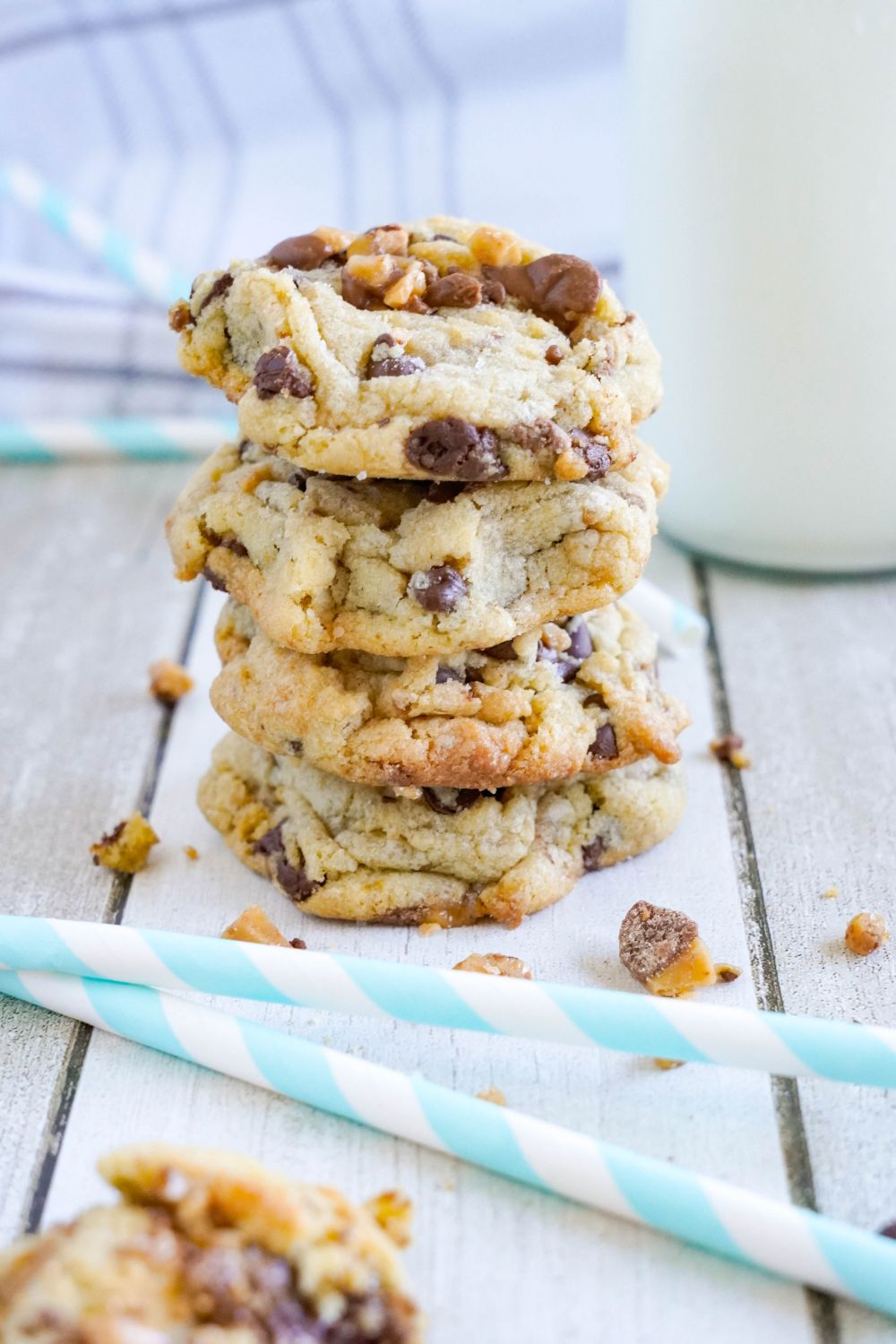 Chocolate Chip Toffee Cookies stacked on top of each other with crumble of cookies around it 