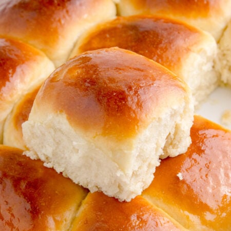 Hawaiian dinner rolls in a baking dish with one removed