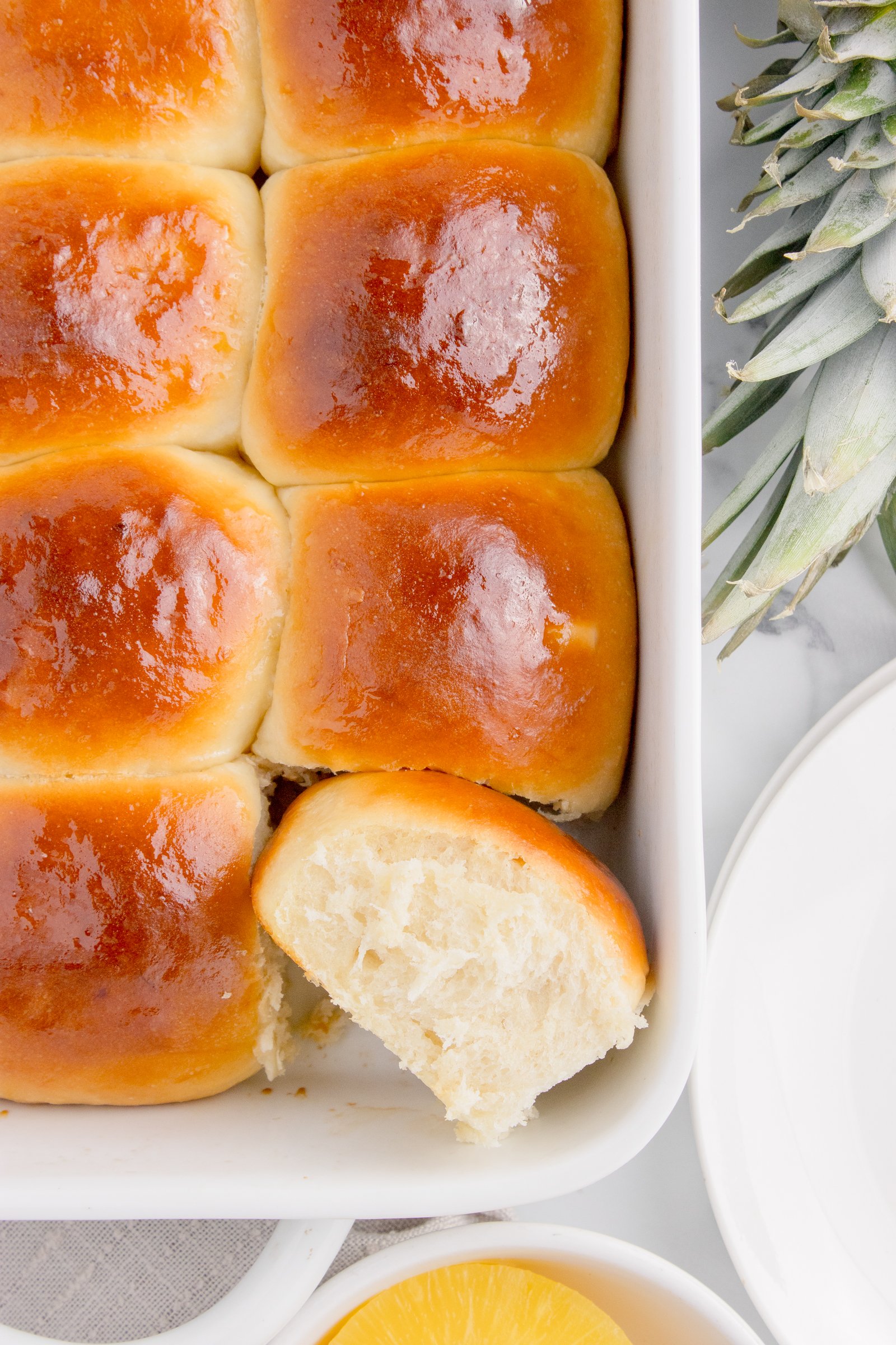 Hawaiian dinner rolls in a baking dish with one on its side showing texture