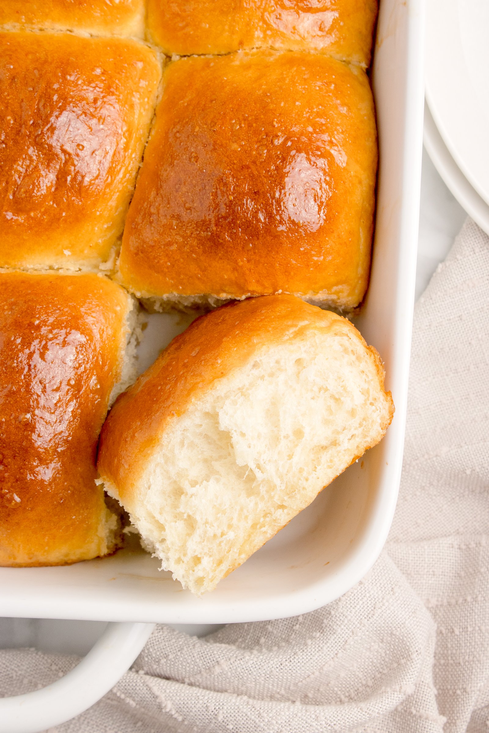 Pull Apart Dinner Rolls in a white baking dish with one cut out showing how delicious