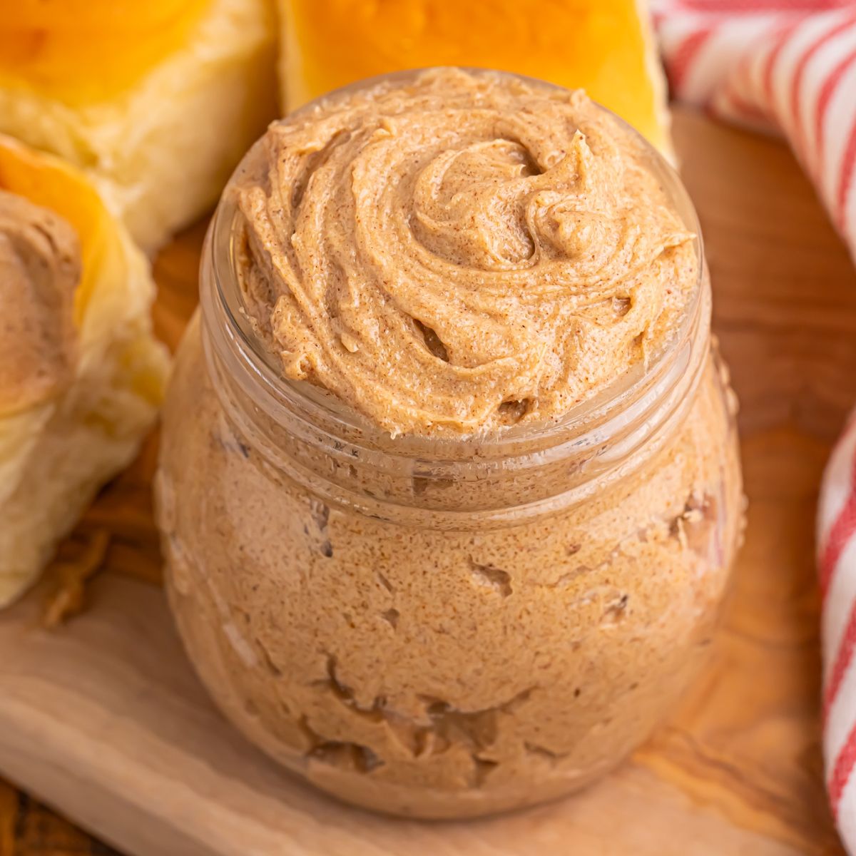 Brown Sugar Cinnamon Butter on counter in a glass jar with rolls behind it