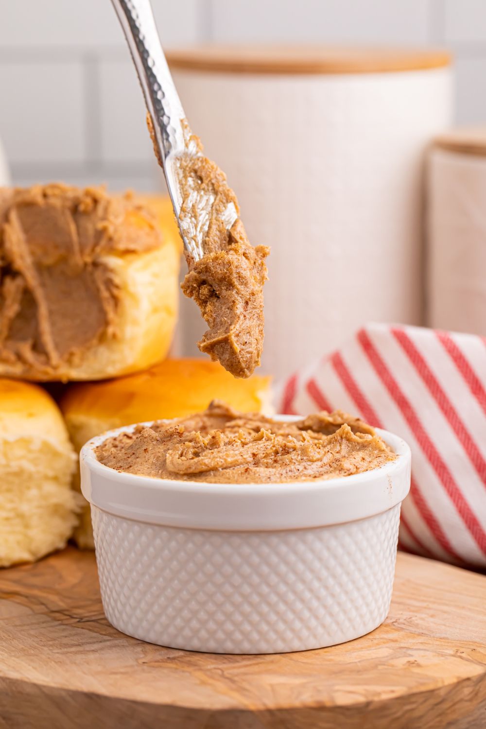Brown Sugar Cinnamon Butter in a white container with a knife with some butter on it being lifted out of container 